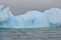 Blue icebergs develop from older, deep glaciers which have undergone tremendous pressure experienced for hundreds of years. The process releases and eliminates air that was originally caught in the ice by falling snow. Therefore, icebergs that have been formed from older glaciers have little internal air or reflective surfaces. When long wavelength light from the sun hits the iceberg, it is absorbed, rather than reflected. The light transmitted or refracted through the ice returns as blue or blue-green. Older glaciers also reflect incident light preferentially at the short wavelength end of the spectrum due to Rayleigh scattering, much in the same way that makes the sky blue.