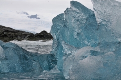 A blue iceberg is visible after the ice from above the water melts, causing the smooth portion of ice from below the water to overturn. The rare blue ice is formed from the compression of pure snow, which then develops into glacial ice. Icebergs may also appear blue due to light refraction and age.