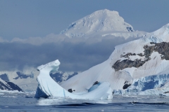Incredible photography. Icebergs in the foreground in twisted shapes with mountains of ice in the background.
