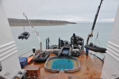 Looking toward the Aft of the ship lifting zodiacs into the Arctic Ocean for expeditions.