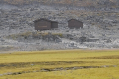 Yellow tundra in the foreground with an old research station in the background.