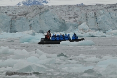 The zodiac zig zags across the frozen ocean water and ice looking at the mammoth size of the face of this glacier.