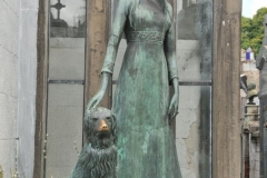 An interesting and unusual tomb is that of Liliana Crociati (de Szaszak). Liliana was 26 years old and, while visiting Innsbruck in 1970 was killed when an avalanche destroyed her hotel. Adjacent to the tomb, which was designed by her mother, is a life-size bronze statue of Liliana in her wedding dress. Subsequently, following the death of her pet dog, a bronze statue of it was added, with Liliana's hand petting its head