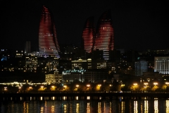 Fire and flames light the buildings in moving reflectons on the harbor at night.