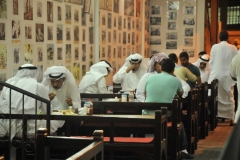 Men enjoying food and tea in an open market restaurant