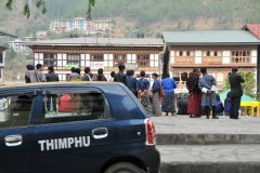 Bhutanese citizens looking onto the square studing the new Toyotas and listening to the music