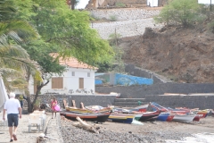 Great photo shot of boats on the beach and a building behind.