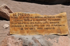 Translation of the sign.  The Wall.  The artistic expressions which mix time and techniques is the picturegraph, the carvings on the walls.   Style Taira, is one of the most renowned rock art styles, the most beautiful of the time.  The reference to the White Raven Santa Barbara referrers to the presence to a group of children belonging to Aymare, people of the highlands of Northern Chile, Peru and Bolivia.  The presence of the llama has an importance100% for their livelihood.