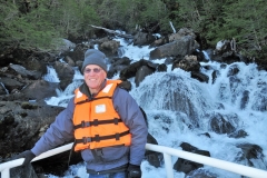 In the midst of all the ice a small green location of life with crashing water from the melting glacier.