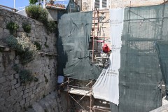 Repairing a residence wall as one walks along the walkway above the city. 