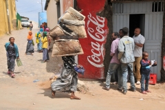 A young lady going to the market. Guys just hanging around.