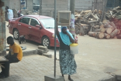 The lady is carrying a square box on her head. How do they do it?