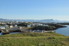Looking across the landscape from atop a hill overlooking Stykkisholmur with ocean and mountains in the distance.