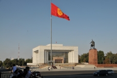 Building with the national flag and soldiers at the side is the National Museum of Kyrgyzstan.  Inside are  interesting exhibitions, ranging from excavation finds to fascinating collections. But for the few Western visitors that make it to Bishkek, the real draw is the weird Soviet memorabilia. The folk hero of Manas on his horse replaced Lenin. Manas is shown slaying a dragon. The epic of Manus was first found written in a Persian manuscript dated to 1792–93. In one of its dozens of iterations, the epic poem consists of approximately 500,000 lines. He is a folk hero.
