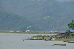 Hang gliders coming in for landing by the lake