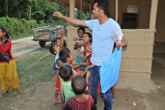 Binoy and the kids making sure each of them gets a piece of candy.
