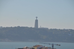 In the distance is the Cristo Rei Lisbon – a gigantic statue of Jesus – stands south of the Lisbon city center across the Tagus River on a hill in Almada. The 92-foot-tall statue of Christ stands on a 269-foot-tall base and is one of the most recognizable of all the Lisbon statues and monuments.