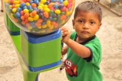 The gum machine is bigger than the kid