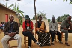 From right to left Sam Nayebare, our tour guide for Rwanda,  local village  leader,  Janet,  the victim that had her family murdered by the man sitting to the far left in the photo, translator and local guide for the day, and Tashia, the perpetrator who killed the family of Janet, the lady seated center  with the orange shawl.