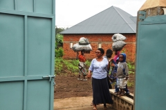 Young boys with their mother. In the background ladies carrying their work for the day on their heads.