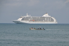 View from the hotel patio, our ship the Regent Seven Seas Voyager, in the distance with a small boat passing in between the ship and the hotel beach area.