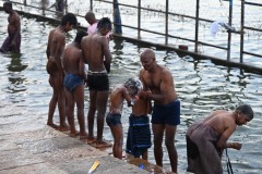 A father helping his children bathe in the river water