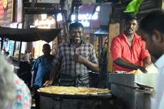 Flat bread is being prepared in front of us on a large flat griddle. 