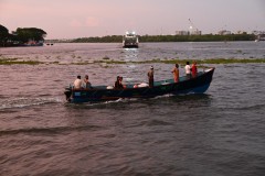 Fishermen in the foreground, vehicle ferry in the center and the port docks in the distance.