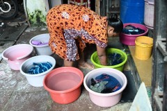 The neighbor next door was washing clothes at her front door outside. 
