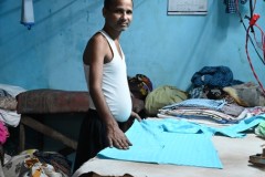 This young man is folding laundry after it being laundered. 