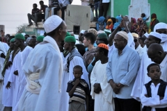 Although Sudan is in many ways a male-dominated society, women find themselves a place in the crowd. They gather in one corner wearing bright, colorful robes. See rear of photo.