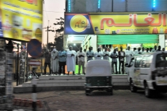 Men working come outside of the business to pray for the evening prayers