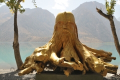 A tree root and trunk cut into a spectacular carving and painted gold.  The back drop of the lake makes this a definite one of a kind viewing.