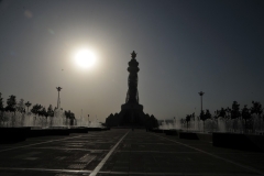 Sun setting in the late afternoon to the left of the tower with the water fountains on each side of the walkway plaza to the street. .