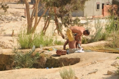 We are near an Artesian well 1,000 feet deep which up wells to the surface where it cools. Here two men are bathing in the water after it has cooled. 