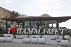 A local restaurant overlooking the seafront with the name of the city in a square in front of the restaurant for photos.