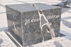 A black labradorite cube with the date of 26 April 1966 inscribed on one of its sides is installed on a granite pedestal. Another side of the cube presents a clock, the hands of which show the time of 5:24. The cube is split by a crack symbolizing the break of the earth and continuing to the foot of the statue, which represents a woman embracing a child and a man trying to protect them with his breast from the strike of the nature.