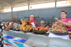 The lady to the  in pink is preparing Plov.  Plov is a rice dish that is cooked in a broth. Depending on its origin, rice pilaf can be accompanied with meat, fish, vegetables, dried fruits or nuts. This method of cooking rice is widespread across the globe. I also say it prepared with horse meat.